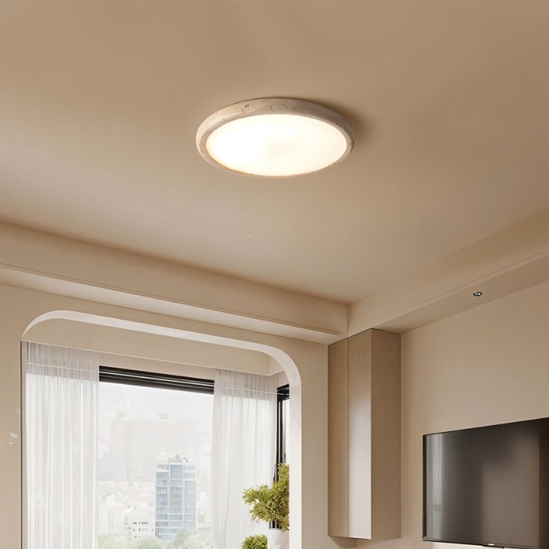 "A modern travertine flush mount ceiling light with a circular design, providing ambient lighting in a contemporary living room."