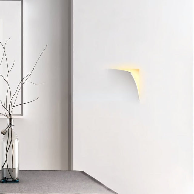 "A recessed trimless wall light casting a soft glow on a white wall in a modern interior setting."