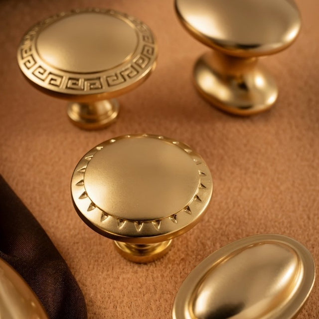 "Close-up of a vintage-style brass cabinet knob with intricate Grecian-inspired detailing."