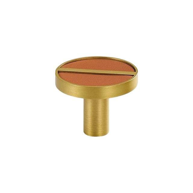 "Circular brass knob with a terracotta leather inlay and a central bar."