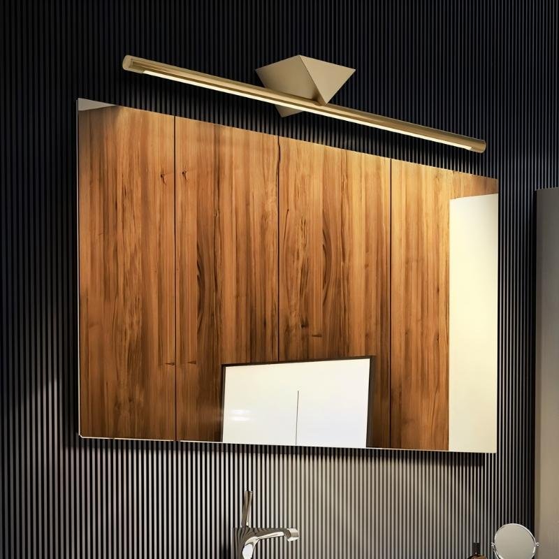 "A modern, linear LED wall lamp with a geometric accent illuminating a bathroom cabinet with a sink."