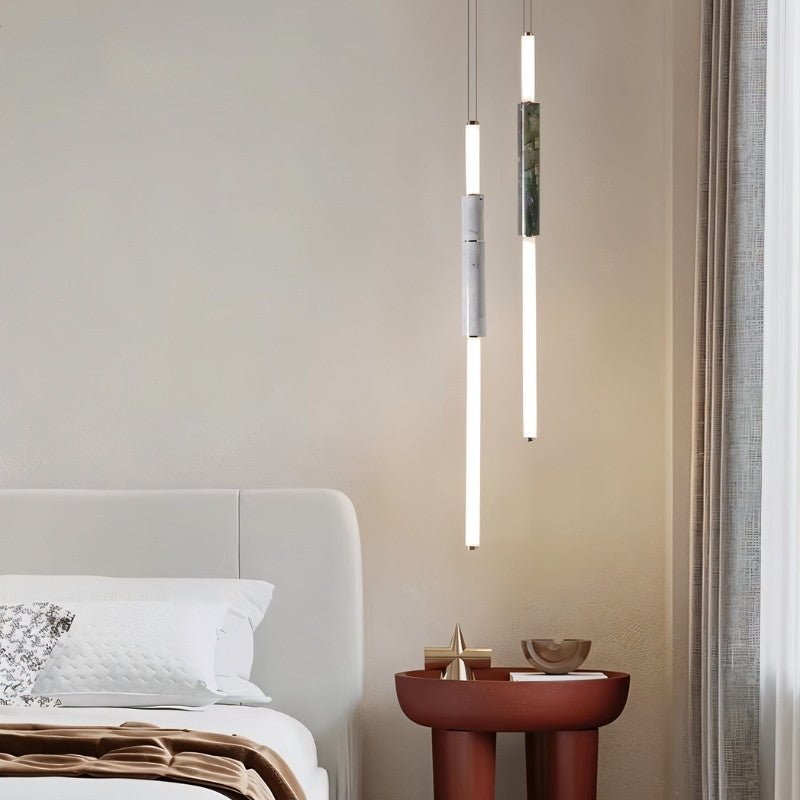 "Modern pendant lights with marble accents and acrylic tubes illuminating a contemporary bedroom."