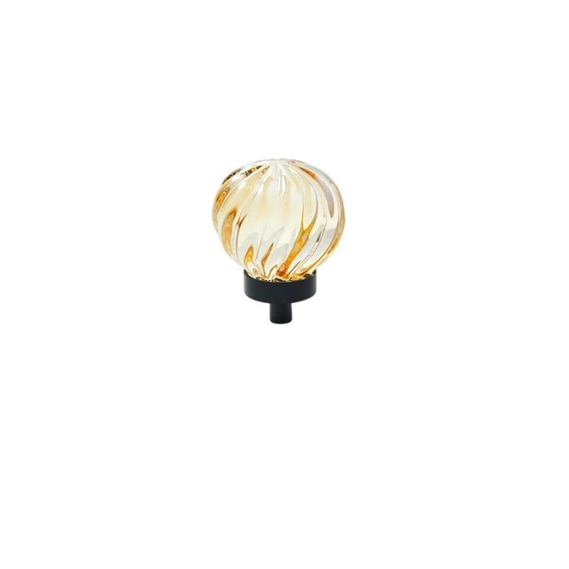 "Amber crystal glass spherical knob with ribbed texture and black base, isolated on a white background."