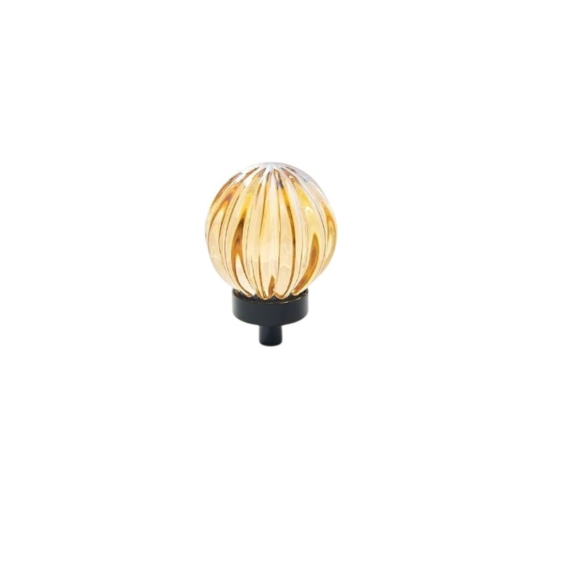 "Amber crystal glass spherical knob with ribbed texture and black base, isolated on a white background."