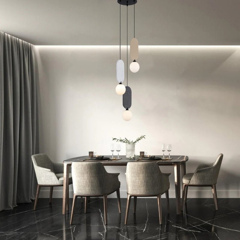 "The Dorea Pendant Lamp, with a spherical glass bulb and metal frame, adds a touch of minimalist elegance to a contemporary dining room setup."