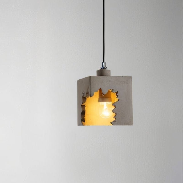 "Concrete pendant light with jagged cutout design, featuring an industrial modern style and warm glow"