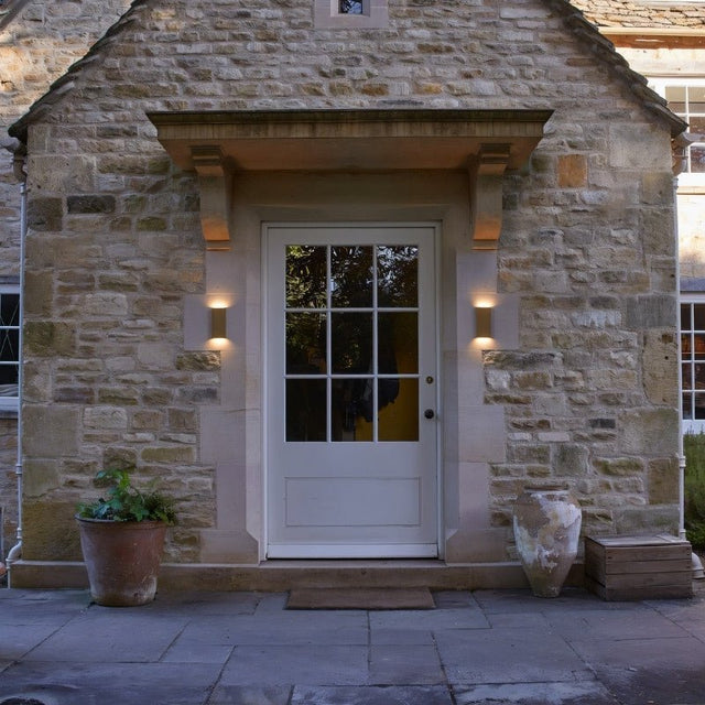 "outdoor wall lamp, warm light on stone house, entryway lighting"