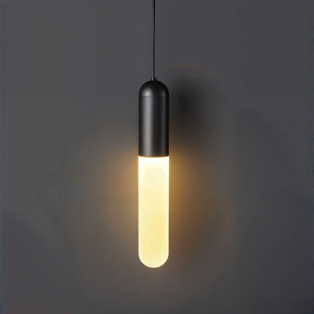 "A minimalist black pendant light with a long, slender cylindrical shade casting a soft, warm glow against a dark gray background."