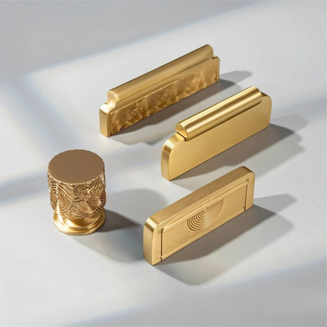 "A collection of textured gold Erdas knobs and pull bar handles on a light background."