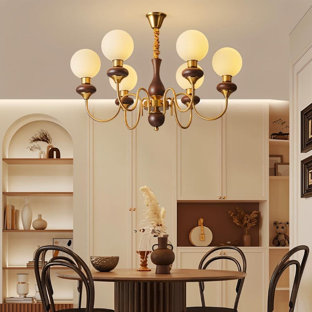 "Gold and dark wood Eurot chandelier with frosted glass globes hanging above a dining table in a traditional dining room."