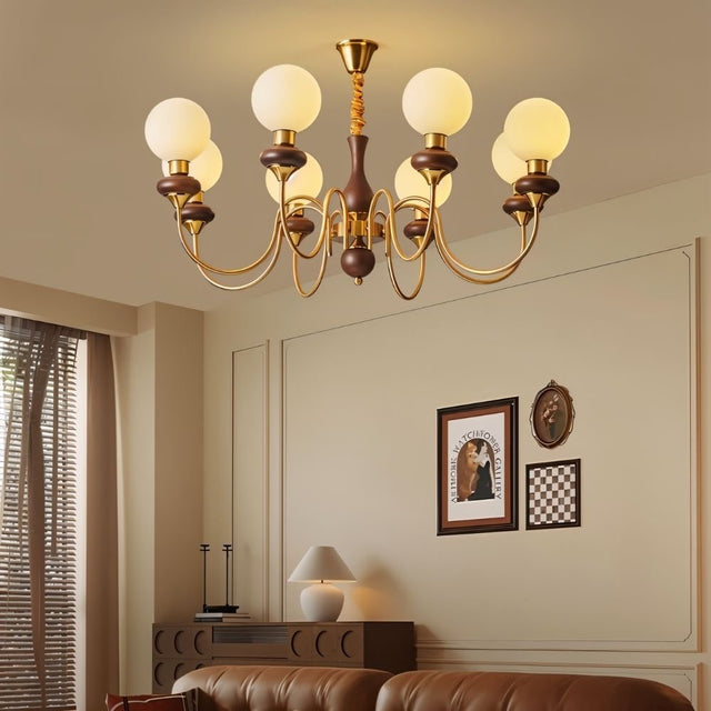 "Gold and dark wood Eurot chandelier with frosted glass globes hanging in a traditional living room with artwork on the wall."