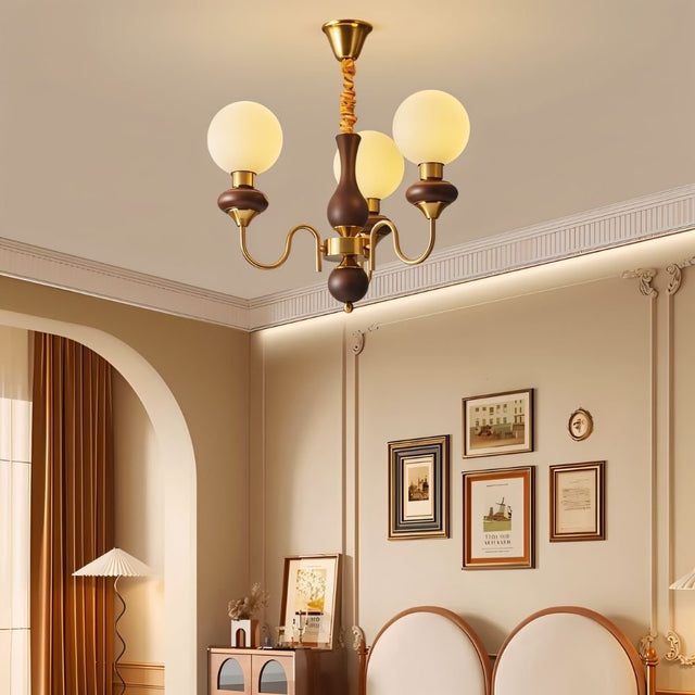 "Gold and dark wood Eurot chandelier with frosted glass globes hanging in a traditional living room."