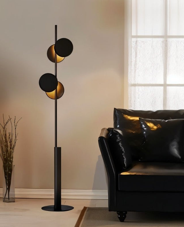 "A modern floor lamp with multiple circular shades, illuminating a living room with a black leather sofa."