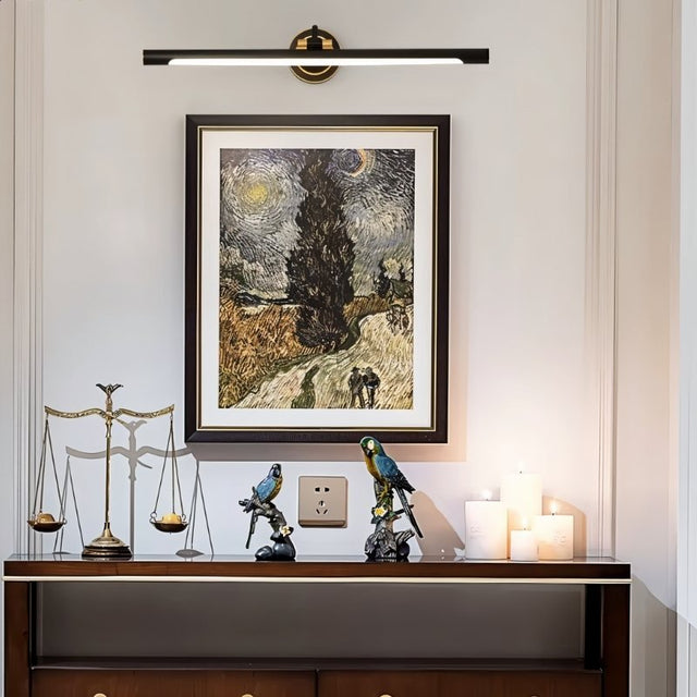 "A sleek black wall lamp with a horizontal bar design, mounted above a framed painting in a contemporary living room, providing focused illumination."