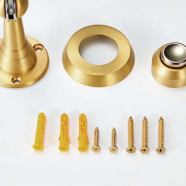 "Figal door stop components and mounting hardware, including screws and wall anchors, in brushed gold and silver finishes."