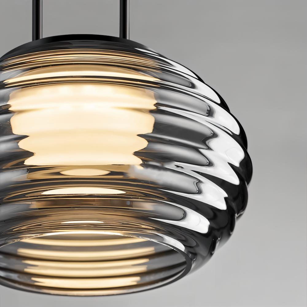"Close-up of a smoky grey Filano pendant light showing the ribbed glass shade and warm diffused glow."