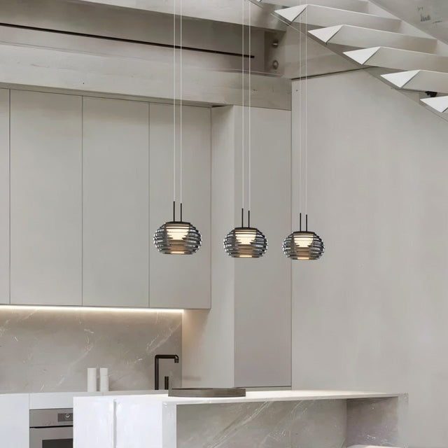 "Three smoky grey Filano pendant lights with ribbed glass shades and iron frames, hanging above a kitchen island."