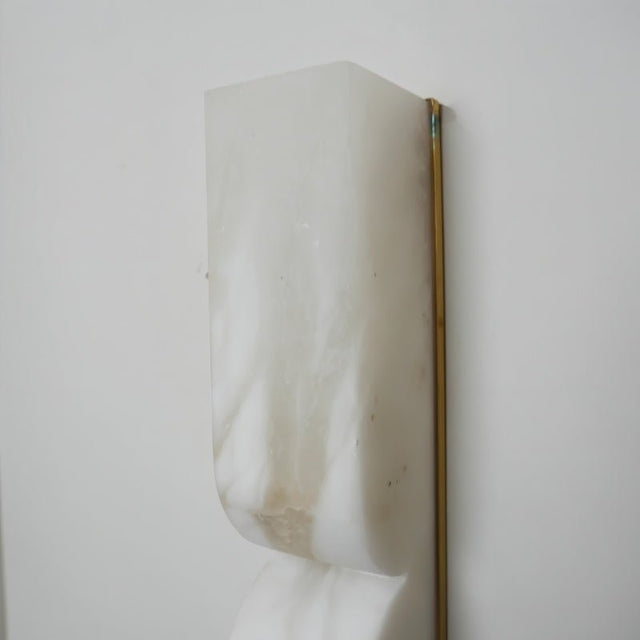 "Detail of a double curved alabaster wall lamp showing the natural stone texture."