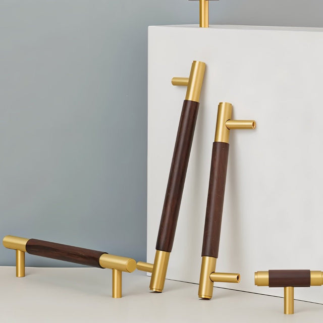 "Set of wood and brass knobs and pull bars with cylindrical design displayed on a white and gray surface."