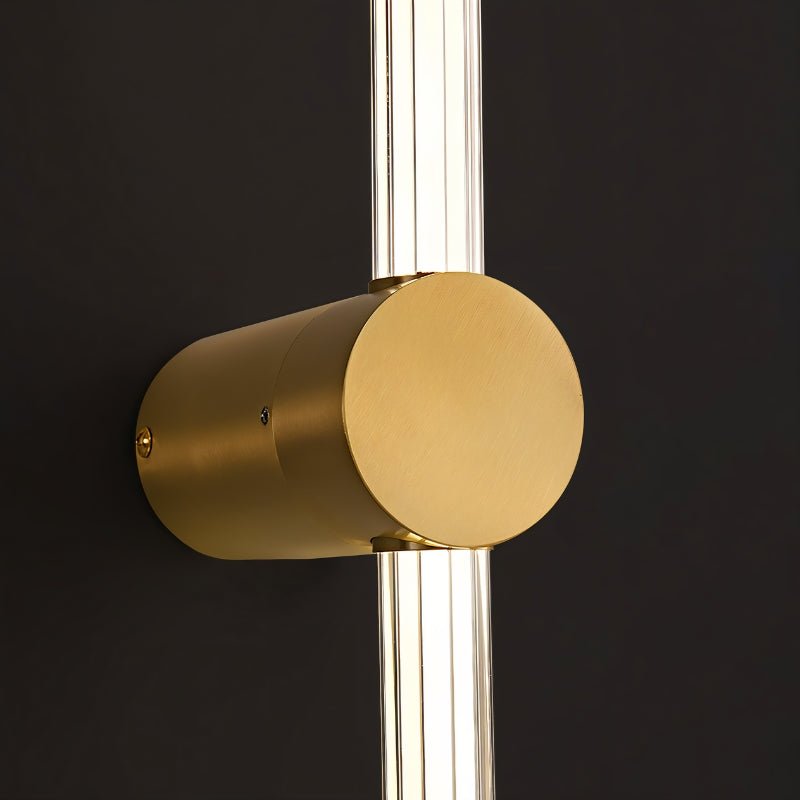 "Close-up of a modern brass wall lamp with an acrylic diffuser, highlighting the cylindrical design and materials."