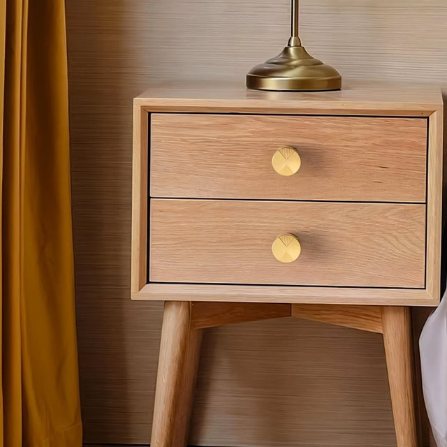 "Round brass knobs with etched geometric detailing on a light wood nightstand."
