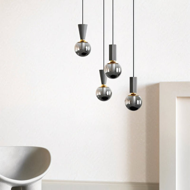 "Group of modern pendant lights with concrete, metal, and smoky glass orbs, creating a stylish focal point in a contemporary space."