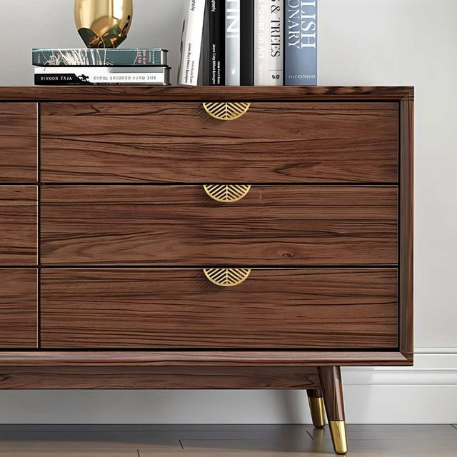 "Gold leaf-shaped drawer pulls on a modern wooden dresser in a living room."