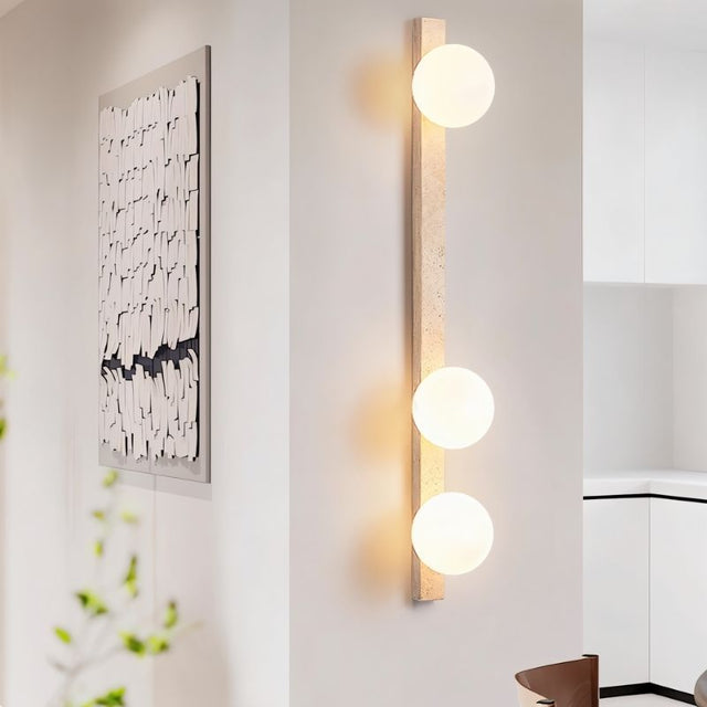 "Tall travertine wall lamp with three frosted glass globes mounted in a stylish interior"