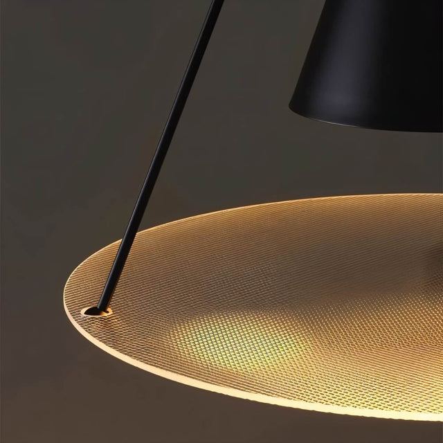 "Close-up of a modern black pendant light with a lit textured glass disc and cone shade."
