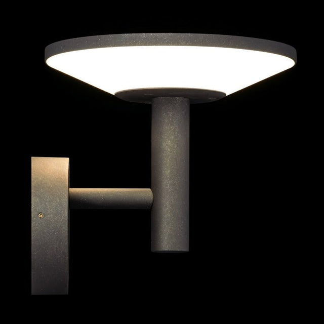 "A modern, circular outdoor wall lamp emitting a bright light against a black background."