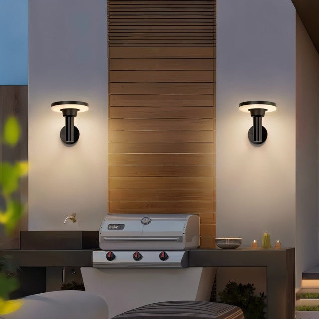 "Two modern, circular outdoor wall lamps mounted on a patio wall, illuminating the space with a warm light."