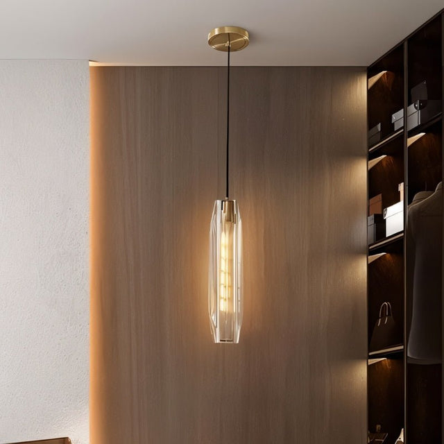 "Elegant pendant light with an elongated, faceted crystal shade and brass frame, providing a captivating glow in a modern walk-in closet."