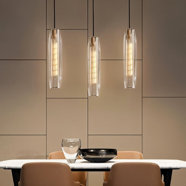 "Elegant pendant lights with elongated, faceted crystal shades and brass frames hanging above a modern dining table, creating a captivating glow."