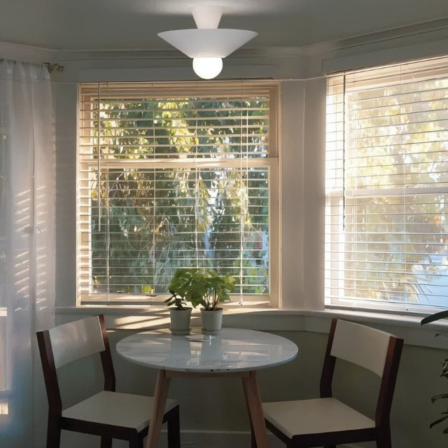 "The Glome Ceiling Lamp, with its modern design made of aluminum, installed in a cozy dining area, illuminating the space with ambient light while serving as a chic focal point."