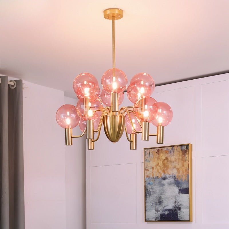 Gloral Chandelier with pink glass bulbs and gold frame, mounted in a modern living room for chic and warm lighting ambiance.