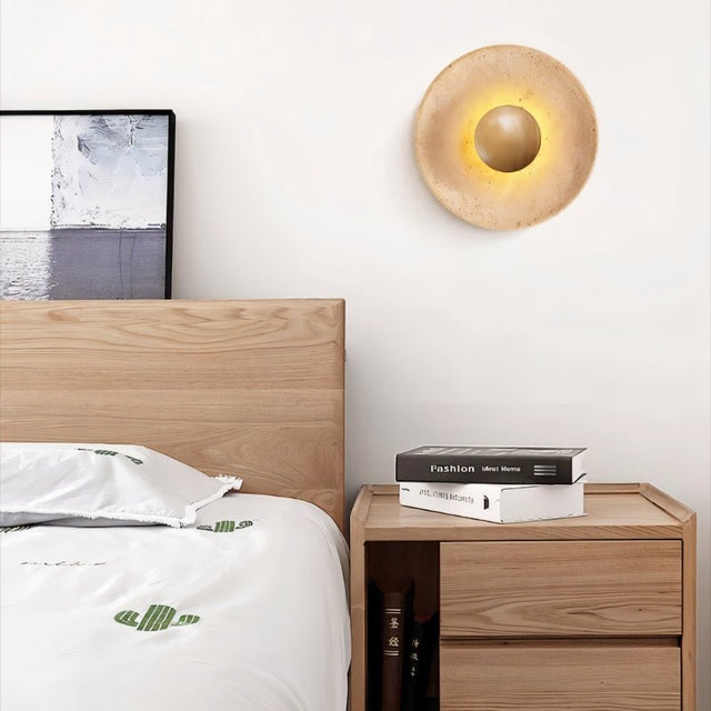 "Three modern, circular wall lamps made of yellow travertine with walnut wood accents, arranged vertically on a wall, providing a warm, ambient glow."
