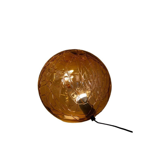 "A modern table lamp with a spherical amber glass shade featuring an intricate pattern, complemented by metal and acrylic accents."