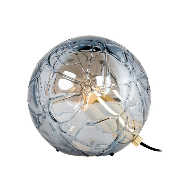 "A modern table lamp with a spherical, patterned glass shade, featuring metal and acrylic accents."