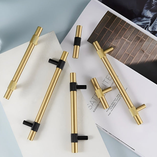 "Assortment of modern brass knobs and pull bar handles with brushed gold finish and black knurled detailing."