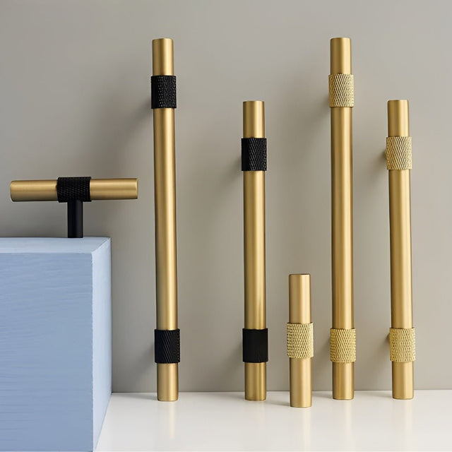 "Modern brass cabinet knobs and pull bar handles with a brushed gold finish and knurled accents."