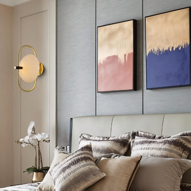 "Brass wall lamp with a frosted glass globe serving as a sconce in a modern bedroom, providing soft, ambient lighting."