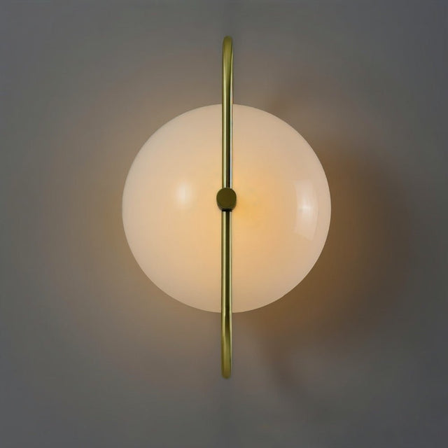 "Close-up of a wall lamp with a brass frame and frosted glass globe, showing its symmetrical design and warm, diffused light."