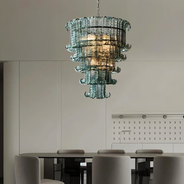"A tiered glass chandelier hanging above a dining table in a dining room."