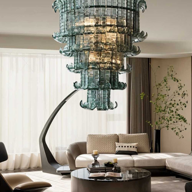 "A tiered glass chandelier in a luxury living room with a curved sofa and round table."