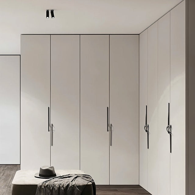 "Black zinc alloy pull bars with flowing curves on a white wardrobe."