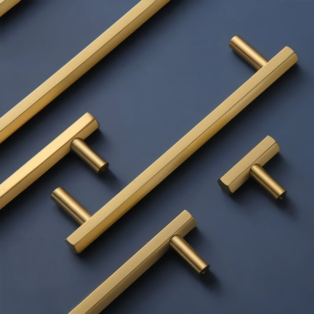 "Modern brass rectangular pull bar handles with cylindrical mounts on a dark blue background."