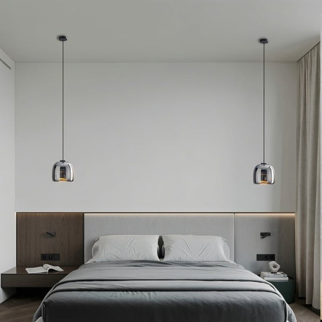 "Two modern pendant lights with smoked glass shades flanking a bed in a minimalist bedroom."
