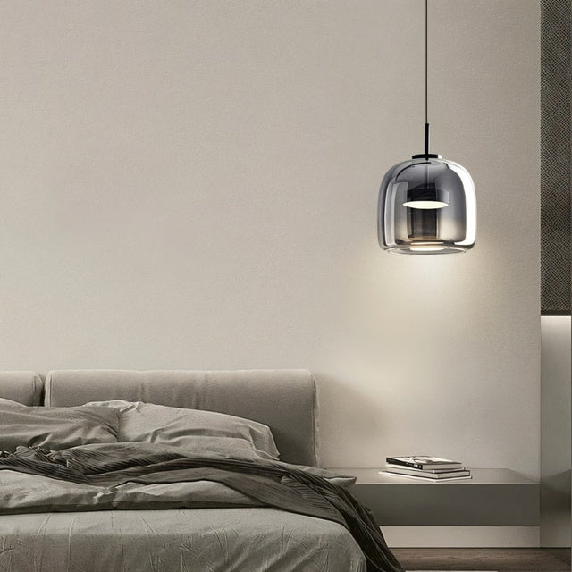 "A modern pendant light with a smoked glass dome shade hanging in a bedroom."