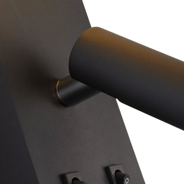 "A close-up of a black wall lamp with a cylindrical spotlight and switches on the backplate."