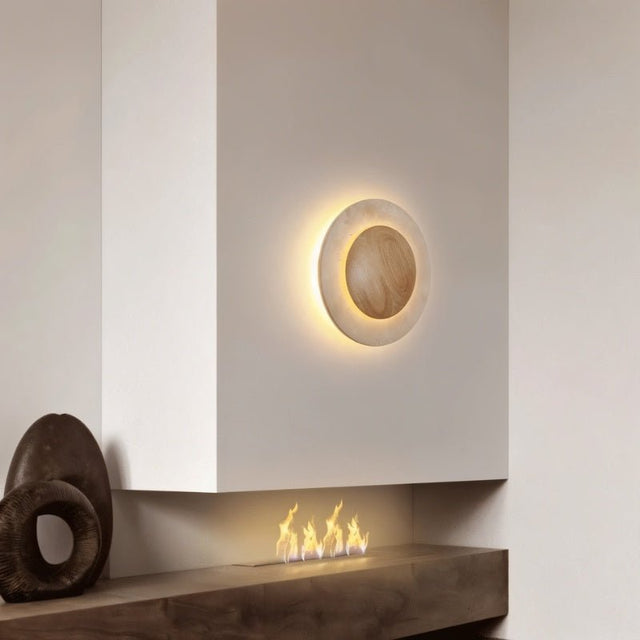 "Circular wall lamp with a travertine stone surround and wood center mounted above a modern fireplace."
